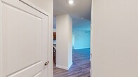 Located at Riverside Plaza in Millsboro, Delaware, this single-floor, 2-bedroom, 2-bathroom residence offers a thoughtfully designed layout with a clean, modern aesthetic throughout. The open-concept kitchen and living area serves as the heart of the home, where rich espresso-toned cabinetry, granite countertops, a central island with a sink, and a full suite of stainless steel appliances — including a refrigerator, range, and microwave — create a functional and stylish cooking space. Recessed lighting illuminates the kitchen, while durable wood-look flooring extends through the main living areas. The living room provides sliding glass door access to an outdoor space, filling the room with natural light and views of the surrounding community. Both bedrooms are carpeted for comfort, with the generously sized primary bedroom featuring a window with natural light. The second bedroom is also well-proportioned and similarly finished. Two dedicated closets offer practical storage, including a walk-in style closet with wire shelving. The two bathrooms are clean and functional, one featuring a soaking tub and shower combination and the other a standalone shower unit, both with brushed nickel fixtures.