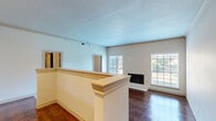 This 2-bedroom, 4-bathroom single-floor residence offers a thoughtfully designed open-concept layout that balances comfort and functionality. Rich hardwood flooring flows throughout the main living areas, creating a warm and cohesive aesthetic. The living room is a welcoming focal point, anchored by a classic fireplace and framed by large windows that invite abundant natural light and outdoor views. A raised kitchen bar with a granite countertop peninsula serves as a natural divider between the kitchen and living space. The kitchen is well-equipped with dark espresso cabinetry, a mosaic tile backsplash, stainless steel appliances, granite countertops, and elegant pendant lighting overhead. The primary bedroom is a generously sized retreat featuring plush carpeting, a ceiling fan, a large window with outdoor views, and direct access to an en-suite bathroom. The bathrooms are finished with granite vanity countertops, dark wood cabinetry, and tile surround showers — including one bath featuring a sleek glass-enclosed walk-in shower with a mosaic tile accent band and built-in bench. The second bedroom is equally comfortable, also featuring carpet flooring and a ceiling fan. Throughout, the space maintains a clean, neutral palette that is both modern and inviting.