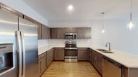 This single-story, one-bedroom, one-bathroom residence in Memphis, Tennessee offers a thoughtfully designed layout with modern finishes throughout. The open-concept living and kitchen area is anchored by warm hardwood-style flooring that extends across the main living spaces, complemented by recessed lighting and a ceiling fan. Natural light filters in through windows with blinds, and a glass-paneled entry door adds brightness to the welcoming living area.

The kitchen is a standout feature, equipped with rich dark-toned shaker cabinetry, light quartz countertops, and a classic white subway tile backsplash. A suite of stainless steel appliances—including a refrigerator with ice maker, electric range, and over-the-range microwave—provides modern functionality. A peninsula with pendant lighting and an undermount sink adds both prep space and visual appeal.

The bedroom is carpeted for comfort, featuring a ceiling fan and a window that allows natural light to flow in. A doorway connects directly to the full bathroom, which offers dark cabinetry with quartz countertops, an undermount sink, a large mirror, and a tub-shower combination, all set over warm hardwood-style flooring. The overall ambiance is clean, contemporary, and move-in ready.