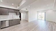 Located at 11110 Hartsook Street in North Hollywood, CA, this modern 2-bedroom, 2-bathroom residence offers a thoughtfully designed open-concept layout with clean lines and contemporary finishes throughout. Light wood-tone flooring flows seamlessly across the entire space, complemented by crisp white walls and recessed lighting that create a bright, airy atmosphere.

The open living and dining area is generously proportioned, featuring a stepped ceiling detail and sliding glass doors that lead to a private balcony with outdoor views. The kitchen is outfitted with dark wood-tone cabinetry, white quartz countertops, a subway tile backsplash, stainless steel appliances including a refrigerator, range, microwave, and dishwasher, and a deep basin sink.

Both bedrooms are well-sized and receive ample natural light through large windows. The primary bedroom includes its own closet and an en-suite bathroom. The primary bathroom showcases marble-look tile flooring, a glass-enclosed shower, a sleek vanity with quartz countertop, and direct access to a walk-in closet with built-in shelving. The second bathroom features matching marble-look tile and a full glass-sliding door tub and shower combination. A hallway connects all rooms with two dedicated closets for additional storage.