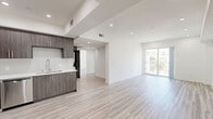 Located at 11110 Hartsook Street in North Hollywood, CA, this modern 2-bedroom, 2-bathroom residence offers a thoughtfully designed open-concept layout with clean lines and contemporary finishes throughout. Light wood-tone flooring flows seamlessly across the entire space, complemented by crisp white walls and recessed lighting that create a bright, airy atmosphere.

The open living and dining area is generously proportioned, featuring a stepped ceiling detail and sliding glass doors that lead to a private balcony with outdoor views. The kitchen is outfitted with dark wood-tone cabinetry, white quartz countertops, a subway tile backsplash, stainless steel appliances including a refrigerator, range, microwave, and dishwasher, and a deep basin sink.

Both bedrooms are well-sized and receive ample natural light through large windows. The primary bedroom includes its own closet and an en-suite bathroom. The primary bathroom showcases marble-look tile flooring, a glass-enclosed shower, a sleek vanity with quartz countertop, and direct access to a walk-in closet with built-in shelving. The second bathroom features matching marble-look tile and a full glass-sliding door tub and shower combination. A hallway connects all rooms with two dedicated closets for additional storage.
