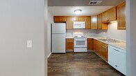 Located at 1692 Granada Dr in Erie, Pennsylvania, this single-floor unit offers a practical and well-organized layout designed for comfortable everyday living. The kitchen is a functional highlight of the space, outfitted with warm honey-toned wood cabinetry, light granite-style countertops, and dark hardwood-style flooring. White appliances including a refrigerator, electric range, and built-in microwave are all present, and ample upper and lower cabinet storage ensures plenty of room for organization. The living and bedroom areas are finished with neutral beige carpet and painted in soft gray tones, creating a calm and cohesive aesthetic throughout. Natural light enters through window treatments in multiple rooms, contributing to a bright and welcoming atmosphere. The bathroom features a clean, white tub and shower combo with chrome fixtures, set against dark wood-style flooring that mirrors the kitchen. White trim and neutral gray walls are consistent throughout the unit, lending a clean and uniform appearance. The overall layout, as seen in the dollhouse view, is compact yet thoughtfully arranged, with clear distinctions between the kitchen, living, and sleeping areas, making the space easy to navigate and utilize efficiently.