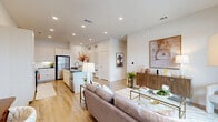 Located at Cibolo Commons in Schertz, TX, this well-appointed one-bedroom, one-bathroom residence offers a thoughtfully designed open-concept floor plan. Light wood-look flooring flows throughout, complementing the bright, neutral palette and recessed lighting that give the space an airy, modern feel.

The living area is anchored by large sliding glass doors that open onto a private patio, filling the room with natural light and providing easy indoor-outdoor access. The kitchen features sleek white flat-front cabinetry reaching to the ceiling, dark granite countertops, a subway tile backsplash, stainless steel appliances, and a central island with a modern sink — ideal for both everyday cooking and entertaining.

The bedroom is a comfortable retreat with windows that invite natural light, a ceiling fan, and direct access to two closets — including a walk-in closet with built-in shelving — as well as the full bathroom. The bathroom is finished with white cabinetry, a dark granite double vanity, black hardware accents, and a glass-enclosed walk-in shower with tile surround. A dedicated laundry area and utility room add everyday practicality, while a hallway nook provides space for a home office setup.