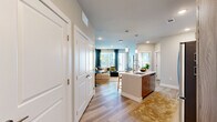 Located at Bravery Heights in Colorado Springs, Colorado, this thoughtfully designed one-bedroom, one-bathroom residence offers a well-appointed single-floor layout with a cohesive modern aesthetic throughout. The open-concept living and kitchen area forms the heart of the home, where light wood-tone flooring flows seamlessly underfoot. The kitchen is equipped with stainless steel appliances—including a French door refrigerator, gas range, and microwave—complemented by a two-tone cabinet design featuring warm wood lower cabinetry and crisp white uppers. A central island with a white countertop and undermount sink provides additional prep space and casual seating. The living room is anchored by a bold accent wall and large windows dressed in teal curtains that invite generous natural light, offering views of the surrounding Colorado scenery. The bedroom features plush carpeting, a large window with mountain views, and access to a generous walk-in closet outfitted with multiple hanging rods and shelving on both sides. The bathroom is finished with wood-toned cabinetry, a white countertop vanity, a black-framed mirror, and a tiled shower-tub combination, all set on light wood-look flooring. Recessed lighting throughout adds a clean, polished feel to every room.