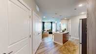 Located at Bravery Heights in Colorado Springs, Colorado, this thoughtfully designed one-bedroom, one-bathroom residence offers a well-appointed single-floor layout with a cohesive modern aesthetic throughout. The open-concept living and kitchen area forms the heart of the home, where light wood-tone flooring flows seamlessly underfoot. The kitchen is equipped with stainless steel appliances—including a French door refrigerator, gas range, and microwave—complemented by a two-tone cabinet design featuring warm wood lower cabinetry and crisp white uppers. A central island with a white countertop and undermount sink provides additional prep space and casual seating. The living room is anchored by a bold accent wall and large windows dressed in teal curtains that invite generous natural light, offering views of the surrounding Colorado scenery. The bedroom features plush carpeting, a large window with mountain views, and access to a generous walk-in closet outfitted with multiple hanging rods and shelving on both sides. The bathroom is finished with wood-toned cabinetry, a white countertop vanity, a black-framed mirror, and a tiled shower-tub combination, all set on light wood-look flooring. Recessed lighting throughout adds a clean, polished feel to every room.