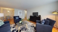 This single-floor residence offers a thoughtfully designed layout that maximizes its generous square footage. The living room serves as the heart of the home, featuring warm hardwood flooring, neutral walls, and a large window that allows abundant natural light to fill the space. The open feel of the room comfortably accommodates a full seating arrangement, making it ideal for both relaxing and entertaining.

The kitchen is well-equipped, showcasing crisp white cabinetry that extends to the ceiling for ample storage, striking dark granite countertops, a stainless steel sink, and white appliances including a dishwasher and range. The tile flooring adds a practical, clean finish to the space.

The bedroom is a serene retreat, highlighted by the same rich hardwood flooring found throughout the home. It offers generous proportions, a large closet with bifold doors, and enough space for a full furniture arrangement. Neutral walls and soft lighting contribute to a calm, restful ambiance.

The bathroom features a tub-shower combination with a decorative striped curtain, a white vanity with under-cabinet storage, and a mirrored medicine cabinet, providing both style and functionality.