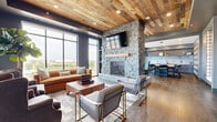 This sophisticated single-floor amenity space offers a generously sized layout thoughtfully divided into distinct functional areas, each finished with high-end materials and cohesive modern design. The centerpiece of the main lounge is a dramatic floor-to-ceiling stacked stone fireplace topped with a wall-mounted television, framed by a reclaimed wood plank ceiling that adds warmth and rustic character to the contemporary interior. Large floor-to-ceiling windows flood the space with natural light and provide expansive outdoor views, while hardwood flooring anchors the seating area where a curated mix of leather and upholstered furnishings creates an inviting social atmosphere. Adjacent to the lounge, a dedicated billiards room features a full-size pool table beneath a striking sputnik chandelier, with industrial-style glass partition walls that maintain visual openness throughout the space. A sleek wet bar and kitchenette offers stone countertops, a double undermount sink with a matte black faucet, open shelving, and bar seating — ideal for entertaining. A secondary lounge nook with patterned carpet tile, a live-edge coffee table, and a large mounted display provides a more intimate viewing or gathering area. The overall ambiance balances industrial and residential influences through a refined palette of gray, wood, and stone tones.