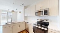 Located at 216 Westheimer Rd in Houston's vibrant Montrose neighborhood, this thoughtfully designed single-floor unit offers an efficient and modern living experience across a well-utilized footprint. Warm hardwood-style flooring runs consistently throughout, lending a cohesive and inviting feel to every room.

The kitchen is a standout feature, outfitted with a full suite of stainless steel appliances — including an electric range, built-in microwave, dishwasher, and refrigerator. Crisp white flat-front cabinetry extends to the ceiling, maximizing storage, while a textured tile backsplash adds subtle visual interest. Globe pendant lights hang above the counter, providing both task lighting and a modern aesthetic touch.

The living room connects seamlessly to the dining area, creating an open and functional layout. Large windows fitted with horizontal blinds allow natural light to fill the space while offering street views of the surrounding Westheimer corridor.

The bathroom is elegantly appointed, featuring a tub and shower combination framed by striking marble-look wall panels with bold veining. White vanity cabinetry and recessed lighting complete the clean, contemporary look. A connecting hallway provides practical flow between the main living spaces and bathroom. Throughout the unit, bright white walls and modern finishes create a clean, move-in-ready environment.