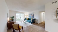 This single-floor residence offers a thoughtfully arranged layout designed for comfortable, everyday living. The living room serves as the heart of the home, featuring plush carpet flooring, a textured ceiling, and a large sliding glass door fitted with vertical blinds that floods the space with natural light and provides access to an outdoor area. The open sightlines and generous proportions make the room highly versatile.

The galley-style kitchen is efficiently designed with warm wood cabinetry, granite-toned countertops, hardwood-style flooring, and black appliances including a refrigerator and electric range. A doorway directly from the kitchen leads into a dedicated laundry room, which houses a full-sized washer and dryer alongside wire shelving for added storage convenience.

The bedrooms are carpeted and bright, each benefiting from windows that allow natural light to enter. One bedroom includes access to a spacious walk-in closet outfitted with wire shelving and ample floor space. The bathroom features a combined tub and shower with tile surround, a wood-toned vanity with granite-style countertops, and hardwood-style flooring. Throughout the residence, neutral tones and consistent finishes create a cohesive and inviting ambiance.