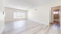 Located at 3910 Coco Ave, Unit 15 in Los Angeles, CA, this 2-bedroom, 2-bathroom unit offers a clean, modern aesthetic across a well-organized single-floor layout. Light wood-style vinyl flooring runs throughout the entire space, creating a cohesive and contemporary look. The living room is bright and open, featuring a textured ceiling, a large window fitted with horizontal blinds that allow ample natural light, and a neutral color palette that enhances the sense of space. The galley-style kitchen is efficiently designed with white shaker cabinetry, dark countertops, stainless steel appliances including a full-size refrigerator, and a double sink — offering a functional cooking environment. Both bedrooms feature the same light flooring, neutral walls, and windows with blinds that bring in natural light. The primary bedroom includes a built-in sliding-door closet with upper cabinet storage, maximizing organization. The two bathrooms are well-appointed, each with white shaker vanities, dark countertops, and wood-style flooring. One bathroom features a tiled tub-shower surround with a window, while the second offers a standalone vanity with a mirror. Clean finishes and consistent design details give the entire unit a refreshed, move-in-ready feel.