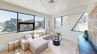 Located in the heart of Phoenix, AZ, this modern single-floor residence offers three bedrooms and two bathrooms thoughtfully arranged in a compact yet efficient layout. The open-concept kitchen and living area serves as the centerpiece of the home, featuring a sleek kitchen with two-tone cabinetry — crisp white uppers paired with dark lower cabinets — stainless steel appliances, and a large island with a quartz countertop and matte black fixtures. An elegant sculptural pendant light anchors the space, while large black-framed windows flood the interior with natural light and frame city skyline views. The living room continues the bright, airy aesthetic with expansive windows on multiple walls, built-in linear ceiling lighting, and light hardwood flooring found throughout the home. Each bedroom is well-proportioned, offering ceiling fans, natural light, and access to closet space. The primary bedroom includes a spacious walk-in closet with built-in shelving and hanging rods. The bathrooms are clean and modern, featuring white tile surrounds, a walk-in shower, light wood-toned vanity cabinetry, and black accent hardware. The overall design is contemporary and cohesive, with a bright white palette, warm wood flooring, and modern fixtures creating an inviting urban retreat.