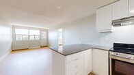Located on Wellington Street West in Ottawa's vibrant Hintonburg neighbourhood, this 2-bedroom, 1-bathroom unit offers a clean, modern living environment across a single floor. Light-toned hardwood flooring runs throughout, lending a cohesive and contemporary feel to every room. The open-concept kitchen and living area form the heart of the unit. The kitchen is outfitted with sleek white cabinetry, dark countertops, a white subway tile backsplash, and stainless steel appliances including a range, dishwasher, and refrigerator. A peninsula with built-in storage provides additional workspace and casual seating options. The living area is bright and airy, with large windows framing views of the surrounding neighbourhood and allowing generous natural light to fill the space. Both bedrooms are well-proportioned, with the primary bedroom featuring a broad window wall that floods the room with daylight. A hallway with closet space connects the bedrooms to the rest of the unit. The bathroom is finished in a clean, all-white palette, featuring a full soaker tub with tiled surround, a white vanity, and a large mirror. The overall design emphasizes simplicity and functionality, making efficient use of the available space.