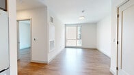 This thoughtfully designed one-bedroom, one-bathroom residence in Boston's Allston neighborhood offers a clean, contemporary aesthetic throughout. Warm wood-look flooring flows seamlessly across the entire unit, complementing the crisp white walls and modern finishes that define the space.

The open-concept kitchen and living area form the heart of the unit. The kitchen is well-appointed with two-tone cabinetry — white upper cabinets paired with soft blue-gray lowers — accented by matte black hardware and a classic white subway tile backsplash. Stainless steel appliances, including a range, microwave, dishwasher, and refrigerator, complete the functional and stylish cooking space.

The living area benefits from a large window framing views of the surrounding Boston streetscape, filling the room with natural light. The bedroom is a comfortable, well-proportioned retreat also featuring a sizable window with city views, and is served by a double sliding-door closet for ample storage.

The bathroom is finished with large-format gray floor tiles, a vanity with modern cabinetry, matte black fixtures, and a frosted privacy window that brings in natural light while maintaining seclusion. Throughout the unit, panel-style interior doors with matte black hardware contribute to the cohesive modern design.