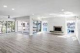 Located along the coveted Bayside Cove in Newport Beach, this single-story home delivers a seamless blend of coastal charm and contemporary design. Light hardwood flooring flows throughout, tying together the clean, bright interiors defined by crisp white walls and recessed lighting.

The expansive living area is a standout, anchored by a stone fireplace and framed by large sliding glass doors that open to a waterfront deck. Breathtaking views of the marina and harbor fill the space with natural light and a sense of openness that defines the coastal lifestyle.

The kitchen is thoughtfully appointed with white shaker cabinetry, stainless steel appliances, a subway tile backsplash, and generous quartz countertops that extend to a large island — ideal for both cooking and entertaining. Plantation shutters throughout the home allow for precise light control and privacy.

The bedrooms are spacious and serene, each featuring ceiling fans and plantation shuttered windows. The bathrooms are elegantly finished with quartz vanity tops, rich dark wood cabinetry, glass-enclosed tile showers, and wide-format mirrors. Every detail reflects a commitment to quality and refined coastal living in one of Newport Beach's most desirable waterfront communities.