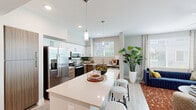 Located in Phoenix, AZ, this thoughtfully designed 2-bedroom, 2-bathroom residence offers a comfortable and modern living experience across a single floor. A welcoming entrance hallway with light wood-style flooring leads into the open-concept kitchen and living area, which serves as the heart of the home. The kitchen is well-appointed with stainless steel appliances, including a side-by-side refrigerator with ice and water dispenser, electric range, microwave, and dishwasher. White upper cabinetry pairs elegantly with warm wood-toned lower cabinets, complemented by a light quartz countertop island with bar seating and stylish pendant lighting overhead. The adjacent living room is bright and airy, featuring a ceiling fan, large windows with outdoor views, and light wood-style flooring that flows seamlessly throughout the space. Both bedrooms are generously proportioned, with large windows that invite natural light and views of the surrounding landscape. The primary bedroom is a comfortable retreat with a ceiling fan and ample space. The two bathrooms are finished with wood-toned vanity cabinetry, light quartz countertops, large mirrors, and tiled shower-tub combinations. Clean neutral tones and modern fixtures unify the design, creating a cohesive and inviting atmosphere throughout.