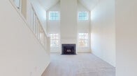 Located at 53 Sand Pit Rd in Danbury, CT, this two-story residence offers a thoughtfully designed layout across two levels. The living room is a standout space, boasting soaring vaulted ceilings that rise dramatically to accommodate a row of upper clerestory windows alongside standard windows below, flooding the room with abundant natural light. A classic fireplace with a dark surround serves as the room's focal point, while plush carpeting and bright white walls create a clean, airy ambiance. A staircase with a white balustrade connects the two floors, visible from the open main level. The kitchen features hardwood-style plank flooring, white cabinetry, granite-style countertops, and black appliances including a gas range, refrigerator, and dishwasher. A tiled backsplash adds texture, and a breakfast bar provides casual dining space. The kitchen also includes access to a utility closet with additional storage. The bathroom is finished with wood-style flooring, a white vanity with ample storage, and a full tub-shower combination. Upper-level rooms are carpeted and receive natural light through wide windows offering views of the surrounding treeline, providing a tranquil setting throughout.