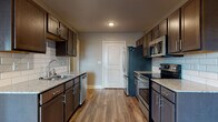 This single-floor residence is thoughtfully designed with a consistent neutral color palette, wood-look flooring throughout the main areas, and clean white trim and crown molding accents. A central hallway connects the living spaces, with doors leading to multiple rooms and providing a clear, organized layout.

The galley-style kitchen is a standout feature, offering dark espresso cabinetry, granite countertops, subway tile backsplash, and a full suite of stainless steel appliances including a refrigerator, range, microwave, and dishwasher. The kitchen opens toward a dining area illuminated by a chandelier and a window that brings in natural light.

The living area is generously proportioned, featuring wood-look flooring, a ceiling fan, and multiple windows along with French doors that allow abundant natural light to fill the space.

Bedrooms are carpeted for comfort, each equipped with ceiling fans and windows offering outdoor views. The primary bathroom features a dual-sink granite vanity with dark cabinetry, a soaking tub with tile surround, and wood-look flooring, creating a refined and functional retreat.