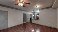 Located at 3204 Wanstead Park Dr in Suwanee, GA, this one-bedroom, one-bathroom unit is thoughtfully designed across a single floor. Rich hardwood flooring runs throughout the main living areas, complemented by crown molding and neutral gray walls that create a clean, modern aesthetic. The open-concept living area is bright and spacious, anchored by a ceiling fan and flows seamlessly into the kitchen. The kitchen is a standout feature, boasting dark espresso cabinetry, granite countertops, a breakfast bar peninsula with pendant lighting, and a full suite of stainless steel appliances including a refrigerator, microwave, and range. The bedroom offers a ceiling fan, a window with natural light, and access to a closet. The bathroom is well-appointed with a subway-tiled tub/shower surround with a decorative accent band, a dark vanity with a marble-style countertop, and hardwood-style flooring. The unit also includes an attached single-car garage with an automatic opener, providing convenient private parking and additional storage. The overall layout is efficient and functional, making excellent use of the available space throughout.