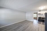 Located at 2580 Wild Pines Lane in Naples, FL, this one-bedroom, one-bathroom unit offers a thoughtfully arranged single-floor layout that maximizes every inch of its compact footprint. Light wood-style flooring runs consistently throughout the space, lending a clean, cohesive aesthetic from room to room.

The kitchen is a standout feature, showcasing white shaker-style cabinetry with sleek hardware, a classic white subway tile backsplash, and granite-look countertops paired with a stainless steel sink. A full-size refrigerator and range complete the functional setup. The kitchen opens directly into the combined dining and living area, creating an open, connected feel that makes the space feel larger than its size suggests. A window at the far end of the living area allows natural light to filter in.

The bedroom offers a comfortable and versatile space, featuring a ceiling fan with light fixture and a window with blinds that frames views of the surrounding greenery. A utility area provides added practicality. The bathroom includes a tiled shower/tub combination with warm earth-toned wall tiles, a white vanity with sink, and a medicine cabinet mirror. Soft gray-blue walls throughout the unit create a calm, neutral backdrop ideal for a variety of décor styles.