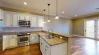Located at 820 N Thompson Lane in Murfreesboro, TN, this well-appointed single-floor home offers a comfortable and cohesive layout across its thoughtfully designed rooms. The open-concept kitchen and living area serves as the heart of the home, showcasing rich granite countertops with warm golden tones, crisp white raised-panel cabinetry, and a decorative tile backsplash. A peninsula with corbel-supported overhang provides additional seating and workspace, while stainless steel appliances — including a refrigerator with ice maker, range, and built-in microwave — add a modern, functional touch. Warm hardwood flooring flows throughout the main living areas, complemented by crown molding that lends an elevated, polished feel. The living room benefits from natural light through sliding glass doors that open to an outdoor view. The spacious bedroom features plush carpeting, a ceiling fan, and a window that draws in natural light. The full bathroom is finished with neutral tile flooring, a tiled tub-surround, a soaking tub, and a vanity with ample storage. A dedicated closet, entrance, and hallway complete the efficient and well-organized floor plan, making this home a refined and practical living space.