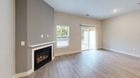 Located at 6420 Harvey St in Muskegon, Michigan, this thoughtfully designed two-story home offers 2 bedrooms and 3 bathrooms across two well-proportioned floors. The main level features an open-concept layout connecting the living room, dining area, and kitchen. The living room is a standout space, highlighted by a gas fireplace set against a neutral accent wall and large sliding glass doors that flood the room with natural light and provide direct outdoor access. The kitchen is outfitted with two-tone shaker cabinetry in white and gray, white quartz countertops, a subway tile backsplash, and stainless steel appliances including a gas range. A convenient half bathroom and dedicated laundry room with full-size washer and dryer complete the main level. Light wood-look flooring runs throughout the main floor, complementing the clean, contemporary aesthetic. Upstairs, both bedrooms feature plush carpet, neutral walls, and generous windows that invite natural light and outdoor views. The primary bedroom is a comfortable retreat with ample square footage. Three bathrooms serve the home, including a full bath with a walk-in shower finished in crisp white. Multiple closets and hallways provide practical storage throughout. The home's clean lines, neutral palette, and modern finishes create a bright, move-in-ready living environment.