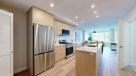 Located at 2900 Tillicum Road in Victoria, BC, this well-appointed two-bedroom, two-bathroom residence offers a thoughtfully designed single-floor layout that maximizes functionality and comfort. Light wood laminate flooring flows consistently throughout, lending a clean, cohesive aesthetic to every room.

The open-concept kitchen and living area forms the heart of the home. The kitchen features flat-panel light wood cabinetry, white quartz countertops, stainless steel appliances including a gas range and French door refrigerator, and a generous island with an integrated sink — ideal for both cooking and entertaining. A stacked washer and dryer is conveniently tucked into the kitchen corridor. The living area is bathed in natural light from a large picture window overlooking mature trees and greenery, creating a serene, inviting atmosphere.

Both bedrooms are comfortable and well-lit. The primary bedroom features a built-in closet, light wood flooring, and a window with outdoor views. The two bathrooms are clean and functional — one features a sliding glass walk-in shower with tile flooring, while the second includes a full bathtub. A welcoming entryway with a warm wood storage bench completes this well-rounded home.
