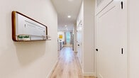 This well-appointed single-story home in Round Rock, Texas offers a thoughtfully designed open-concept layout across two bedrooms and two bathrooms. Light wood-look flooring flows seamlessly throughout, complemented by crisp white walls and recessed lighting that create a bright, airy atmosphere.

The modern kitchen is a standout feature, boasting sleek white cabinetry extending to the ceiling, a wall-mounted range hood, stainless steel appliances including a French door refrigerator and electric range, and a generous white quartz island with bar seating — ideal for both cooking and casual dining. Natural light filters in through window treatments, enhancing the clean, contemporary aesthetic.

The open living area offers ample space for lounging and entertaining, with multiple windows and a glass-panel door providing views and access to the outdoors. A dedicated dining area with a marble-top table adds a refined touch.

The primary bedroom features a calming color palette with a cool gray accent wall and generous proportions. The second bedroom is equally comfortable. Both bathrooms are finished with neutral tile, including a full tub-shower combination with large-format wall tile and light wood-look flooring.

A wide entry hallway with recessed lighting connects each space efficiently, completing this polished and functional home.