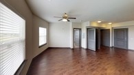 This single-floor unit presents a contemporary design aesthetic carried consistently throughout its living spaces. The open main living area features rich, dark hardwood-style flooring and neutral-toned walls, with a ceiling fan overhead and a large window fitted with blinds that invites natural light into the space. Multiple doorways connect to additional rooms, creating an accessible and functional layout.

The kitchen is a standout feature, showcasing floor-to-ceiling dark wood cabinetry with sleek bar-pull hardware, light granite countertops, and a textured tile mosaic backsplash that adds visual depth. Black stainless appliances—including a range, built-in microwave, refrigerator, and dishwasher—complete the modern culinary space. Track lighting above enhances visibility and reinforces the contemporary style.

The bedroom continues the neutral palette with wall-to-wall carpeting, a ceiling fan, and a window offering an outdoor view, creating a comfortable and quiet retreat.

The bathroom is clean and functional, featuring a full soaking tub with a curved shower rod, a wall-mounted dark wood storage cabinet, and simple, bright finishes that maintain the unit's cohesive modern character throughout.