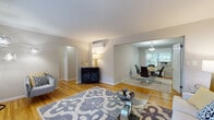 This single-floor residence offers a thoughtfully designed layout that balances comfort and functionality throughout its interconnected living spaces. Warm hardwood flooring flows consistently through the main living areas, lending a cohesive and inviting character to the home.

The living room is bright and welcoming, with a large window that draws in natural light and overlooks greenery outside. A wall-mounted split-unit HVAC system provides climate control, and the space connects seamlessly to the dining area, which is defined by a pendant light fixture overhead and its own window that further brightens the room.

The kitchen features rich, dark espresso-toned cabinetry paired with granite-look countertops and black appliances, including a gas range and refrigerator. Light tile flooring grounds the space and contrasts stylishly with the cabinetry.

Both bedrooms are generously proportioned, each featuring hardwood floors, natural light from windows, and access to closet space. The primary bedroom also includes a wall-mounted split-unit for personalized climate control.

The bathroom is clean and classic in design, with white subway-style wall tiling, a vanity with ample counter space, and a round mirror above the sink.

Overall, this residence offers a neutral, modern aesthetic with practical finishes and a well-connected floor plan ideal for comfortable everyday living.