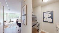 This thoughtfully laid-out one-bedroom, one-bathroom residence offers a comfortable and efficient use of space across a single floor. The open living area is a standout feature, bathed in abundant natural light through floor-to-ceiling windows dressed with sheer vertical blinds that offer both privacy and a connection to the lush greenery outside. Light hardwood flooring runs throughout, lending warmth and continuity to the space.

The kitchen is compact yet functional, equipped with stainless steel appliances including a refrigerator and a coil-burner range, white cabinetry, light countertops, and a stainless steel sink — offering everything needed for everyday cooking.

The bedroom is a serene retreat, comfortably sized and featuring the same expansive windows as the living area, inviting natural light and outdoor views. The bathroom is clean and well-appointed, with a tub-shower combination, a white vanity, and tasteful décor accents.

Additional conveniences include a dedicated laundry area and a hallway that connects the rooms efficiently. Neutral tones, clean lines, and consistent flooring throughout the unit create a cohesive, modern aesthetic that is both inviting and practical.