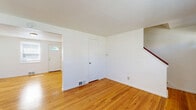 Located at 6A Weis Rd in Albany, NY, this two-bedroom, one-bathroom home is distributed across three floors, offering a practical and well-organized layout. Warm-toned hardwood flooring runs throughout the main and upper living areas, lending a cohesive, classic feel to the interior. Crisp white walls and textured ceilings complement the natural light that filters in through blinds-fitted windows in nearly every room.

The main level features two living areas connected by a staircase, with one living space anchored by the front entry door and a bright window with neighborhood views. The compact kitchen is outfitted with white cabinetry, dark laminate countertops, tile flooring, a gas range, and a window above the sink that brings in natural light.

Upstairs, the two bedrooms are well-proportioned, with the primary bedroom benefiting from dual windows that brighten the space considerably. Both rooms feature the same warm hardwood flooring and clean white finishes. The full bathroom showcases vintage-style character with cream and navy tile wainscoting, a mosaic tile floor, a soaking tub, pedestal vanity, and a framed mirror.

The basement level provides utility space housing the water heater and additional storage, with an exposed ceiling and painted concrete floors. Staircases connect all three levels seamlessly throughout the home.