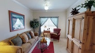 This single-floor residence offers a thoughtfully organized layout with distinct living spaces that flow naturally from one area to the next. The living room serves as the heart of the home, featuring crown molding, soft carpet flooring, a ceiling fan, and a large window dressed with sheer draping curtains that invite natural light while maintaining privacy. The space comfortably accommodates generous seating arrangements and decorative accents that contribute to its warm, welcoming ambiance.

Adjacent to the living area is a dedicated dining nook, a cozy and intimate space framed by a window that adds a touch of natural brightness to mealtimes. The galley-style kitchen is efficiently designed with dual-sided countertops featuring granite-look surfaces, ample white cabinetry extending to upper shelves, a double sink, and a full suite of white appliances including a range, microwave, and refrigerator. Wood-look flooring runs throughout the kitchen, adding warmth and durability.

The bedroom is a serene retreat with plush carpet, a ceiling fan, and a window that allows natural light to fill the room. The full bathroom offers a long vanity with a granite-look countertop, generous cabinet storage, a large mirror, and wood-look flooring. A utility closet houses the water heater and includes built-in shelving, completing the practical offerings of this well-rounded residence.