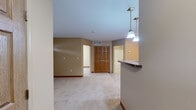 Located at 1410 Deer Lakes Dr in Buffalo, NY, this one-bedroom, one-bathroom unit offers a practical and well-organized single-floor layout. The galley-style kitchen is equipped with warm-toned wood cabinetry, light countertops, a double-basin sink, a dishwasher, a refrigerator, and light wood-look flooring. A window at the end of the kitchen allows natural light to brighten the space. The bedroom features neutral carpet flooring, warm beige walls accented by wood baseboards, a ceiling fan with a light fixture, and a window fitted with blinds that provides a view of the surrounding greenery. A dedicated closet offers convenient storage directly off the bedroom area. The full bathroom includes a combination tub and shower, a warm wood vanity with an under-sink cabinet, a wall-mounted mirror, and tile flooring in a neutral tone. Throughout the unit, the color palette remains consistent with soft beige tones and wood accents, contributing to a cohesive and understated aesthetic. The single-floor design ensures ease of navigation, and the overall layout makes efficient use of the available space.