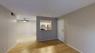 This single-floor unit offers a clean, functional layout designed for comfortable everyday living. The open living and dining area is finished with warm, large-format tile flooring and features a ceiling fan overhead. A textured ceiling runs throughout the space, adding a classic residential touch. A distinctive accent wall with a pass-through window connects the living area to the kitchen, creating an open and communicative flow between the two spaces.

The kitchen is well-equipped and practical, featuring white cabinetry with ample storage, gray laminate countertops, a subway tile backsplash, and stainless steel appliances including a range, refrigerator, and dishwasher. Recessed lighting illuminates the kitchen, and a utility door at the rear provides additional access.

The bedroom is a calm, neutral-toned room with natural light streaming in through a window fitted with blinds, continuing the light tile flooring found throughout. A sliding-door closet offers generous storage space with a full-width hanging rod.

The living room also features a sliding glass door covered by vertical blinds, allowing for natural light control and potential outdoor access. Overall, the space presents a cohesive, neutral palette of grays and warm whites, creating a bright and move-in-ready environment.