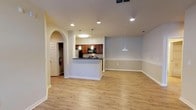This well-appointed 3-bedroom, 2-bathroom single-story residence offers a thoughtfully designed open-concept layout that seamlessly connects the living, dining, and kitchen areas. Light wood-look flooring flows throughout the main living spaces, complemented by neutral-toned walls and recessed lighting that create a bright, welcoming ambiance. The kitchen is a functional highlight, featuring rich dark wood cabinetry, dark granite-style countertops, stainless steel appliances including a refrigerator, electric range, microwave, and dishwasher, and a peninsula with pendant lighting that doubles as a casual dining area. A distinctive arched entryway adds an architectural touch connecting the kitchen to the living area. The expansive living room is fitted with a ceiling fan and offers ample space for flexible furniture arrangements. Each of the three bedrooms is carpeted for comfort, includes a ceiling fan, and receives natural light through windows with blinds. The two bathrooms are finished with rich wood vanities, light countertops, framed mirrors with overhead lighting, and tub-shower combinations with tile surrounds. Wood-look flooring carries through the bathrooms, adding a cohesive design element. The overall layout is practical and comfortable, making efficient use of the generous square footage available.