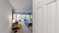 Located at 14120 Weeping Willow Dr in Silver Spring, MD, this 2-bedroom, 2-bathroom residence offers a thoughtfully organized single-floor layout designed for comfortable everyday living. The living room features plush carpeting, neutral gray walls, and a large sliding glass door that opens to a private balcony, filling the space with natural light and outdoor views. Two dedicated dining areas provide flexible options for casual and formal meals, both illuminated by pendant lighting and accented with soft carpet underfoot. The galley-style kitchen is equipped with warm honey-toned wood cabinetry, dark countertops, black appliances including a gas range and refrigerator, and hardwood-style flooring, with a direct sightline into the dining area. The primary bedroom offers a generous, comfortable retreat with carpeted floors and natural window light. The second bedroom is equally well-appointed with carpet and a bright window. Both bathrooms feature white vanities and tiled finishes; one includes a shower-tub combination with tile surround, while the other offers a vanity with wood-style flooring. A hallway and closet provide additional storage throughout. The overall aesthetic is clean, modern, and neutral, creating a versatile and inviting atmosphere throughout.