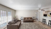 Located at 500 Rolling Hills Pl in Lancaster, TX, this single-story 2-bedroom, 1-bathroom home offers a practical and well-organized layout with consistent wood-look flooring and neutral tones throughout. The combined living room and kitchen area forms the heart of the home, anchored by a cozy fireplace and large French doors that allow natural light to fill the space. The living room offers a comfortable, open feel with a textured ceiling and easy access to the front entry. The kitchen features white cabinetry, marble-look countertops, a tile backsplash, and black appliances including an electric range and refrigerator. A peninsula with a breakfast bar and ceiling fan connects the kitchen to the living area, making it ideal for casual dining. The primary bedroom includes a ceiling fan, a walk-in closet, and a window providing natural light. The second bedroom also features a ceiling fan, a window, and ample space. Both bedrooms share a full bathroom appointed with a white vanity, marble-look countertops, a medicine cabinet, and a tub-shower combination. A hallway with two closets provides additional storage throughout the home, rounding out this efficiently designed and move-in-ready residence.