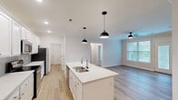 Located at 6600 Man O War Blvd in Lexington, Kentucky, this well-appointed 2-bedroom, 2-bathroom residence offers a thoughtfully designed single-floor layout with clean, contemporary finishes throughout. Light wood-tone flooring runs seamlessly across the main living areas, complementing the bright, neutral color palette that defines the space.

The open-concept kitchen and living area serves as the heart of the home. The kitchen features a central island with a double-basin sink, crisp white cabinetry, light quartz countertops, a subtle tile backsplash, stainless steel appliances, and stylish black pendant lighting. Crown molding adds a refined touch to the living area, which benefits from abundant natural light through large windows and direct outdoor access via a glass-panel door leading to a balcony. A ceiling fan keeps the space comfortable year-round.

Both bedrooms are well-sized with large windows that frame leafy outdoor views and include closet storage. The bathrooms are finished with white cabinetry, quartz vanity tops, and light wood-tone flooring. A dedicated laundry room houses a full-size washer and dryer with overhead wire shelving for added storage. A hallway and additional closet complete the functional, efficient floor plan.