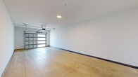 Located at 1200 S 44th St in Rogers, Arkansas, this single-level garage offers a well-proportioned, open layout designed for both vehicle storage and versatile use. The space is defined by its clean, minimalist aesthetic, with smooth white walls accented by dark baseboards that provide a crisp visual contrast throughout.

The flooring consists of durable, polished concrete that spans the entire area, offering a practical and low-maintenance surface suitable for a variety of purposes. A standout feature is the contemporary garage door, which incorporates horizontal glass panel inserts that allow natural light to filter into the interior, lending the space a brighter, more open feel than a traditional garage.

The door is equipped with a ceiling-mounted automatic opener, with the rail system running centrally along the ceiling for efficient operation. Recessed ceiling lighting provides consistent illumination throughout the space. A standard entry door is also present along one wall, offering convenient interior access.

The open floor plan and generous proportions make this garage well-suited for vehicle storage, a workshop, or additional utility space. The overall condition and modern detailing reflect a well-maintained, move-in-ready space.