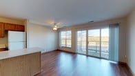 This well-organized single-floor residence offers a practical and comfortable layout designed for everyday living. The open-concept living and dining area is a standout feature, showcasing rich hardwood-style flooring that extends throughout the main living spaces. A ceiling fan adds comfort overhead, while a large window and sliding glass door flood the room with natural light and provide direct access to a private balcony with outdoor views — an ideal spot for relaxing or entertaining. A kitchen peninsula with warm oak cabinetry separates the kitchen from the living area, creating a functional divide while maintaining an open feel. The kitchen is equipped with ample cabinet storage, a coil-top range, an over-the-range microwave, a refrigerator, and a double sink with surrounding counter space. Two bedrooms are finished with plush carpeting, providing a comfortable retreat. Each bedroom includes closet storage, and one features a generously sized window that brings in abundant natural light. The full bathroom is clean and straightforward, offering a shower-tub combo, a vanity with storage, and hardwood-style flooring consistent with the rest of the home. The neutral color palette throughout lends the space a bright, move-in-ready appeal.