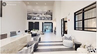 This expansive single-floor amenity space delivers an impressive blend of contemporary design and functional versatility across a generously scaled floor plan. The grand lobby entrance sets the tone immediately, showcasing soaring double-height ceilings, bold black-and-white striped tile flooring, and a striking large-format aerial photography mural mounted high on the wall. A reception desk anchors the space, while seating areas with modern furnishings invite guests to linger.

The living room area features a dramatic accent wall with an intricate dark geometric pattern, white sectional seating, and sculptural black coffee tables, creating a stylish social hub. Nearby, a dedicated office area impresses with floor-to-ceiling vertical light fixtures, marble-clad surfaces, and an executive desk arrangement framed by coffered architectural detailing.

The kitchen and living room combine into a showpiece gathering area, centered on an expansive marble-topped island with bar seating and gold-toned pendant lighting suspended above. Herringbone wood-look flooring, navy cabinetry, and a full appliance suite complete this chef-quality space.

A game room offers foosball, shuffleboard, and card tables beneath soaring ceilings and a statement pendant fixture. Additional lounges provide tufted booth seating for co-working or socializing, while hallways and a laundry room round out the thoughtfully designed layout.
