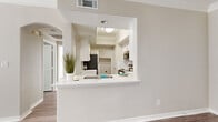 This well-appointed one-bedroom, one-bathroom unit in Round Rock, Texas offers a functional and modern layout across a single floor. The open-concept kitchen and living area serves as the heart of the home, connected by a pass-through window with a built-in breakfast bar. The kitchen is outfitted with white shaker cabinetry, white quartz countertops, a classic subway tile backsplash, stainless steel appliances including a refrigerator, range, microwave, and dishwasher, and warm wood-style vinyl plank flooring that flows throughout the unit. Crown molding adds a refined touch to the living spaces. The bedroom is a comfortable retreat featuring wood-style flooring, crown molding, a ceiling fan, and large windows with blinds that invite ample natural light. The full bathroom includes a white vanity with cabinet storage, a tub-shower combination, and matching wood-style flooring. A dedicated laundry room provides added convenience with a full-size washer and dryer. The unit also includes an attached single-car garage with an automatic opener, offering secure parking and additional storage. The overall aesthetic is clean, bright, and modern throughout.