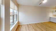 Located at 900 3rd St SE in Cedar Rapids, Iowa, this well-appointed one-bedroom, one-bathroom unit offers a generous and efficiently designed single-floor layout. The open-concept kitchen and living area serves as the heart of the home, featuring light wood-style flooring, warm neutral tones, and an abundance of natural light through large windows with views of the surrounding neighborhood. The kitchen is outfitted with crisp white shaker cabinetry, stainless steel appliances including a range, microwave, and refrigerator, white quartz countertops, a peninsula with an integrated sink, and stylish pendant lighting overhead — ideal for both cooking and casual dining. The living area flows seamlessly from the kitchen, providing a bright and versatile space. The bedroom offers comfortable carpeting, a ceiling fan, and a window with outdoor views, creating a calm and restful retreat. The full bathroom is cleanly finished with a white vanity, wood-look flooring, and a shower-tub combination. A dedicated laundry area houses a stacked washer and dryer unit alongside wire shelving for added storage. Throughout the unit, consistent warm beige walls, clean white trim, and cohesive finishes create a modern yet inviting atmosphere.