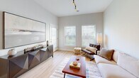 Located at 1100 Jericho Turnpike in Commack, NY, this one-bedroom, one-bathroom unit offers a well-designed single-floor layout with a thoughtful use of space throughout. Light wood-look flooring flows seamlessly across all rooms, creating a cohesive and warm aesthetic complemented by a neutral color palette of soft whites and grays.

The open-concept kitchen and living area serves as the heart of the unit. The kitchen is equipped with white shaker cabinetry extending to the ceiling, a classic subway tile backsplash, stainless steel appliances including a refrigerator, range, and microwave, and a white quartz peninsula with bar seating illuminated by pendant lighting. Track lighting adds a modern functional touch overhead.

The living room benefits from multiple windows that invite natural light and provide outdoor views, contributing to an airy and bright atmosphere. High ceilings further enhance the sense of openness throughout this shared space.

The bedroom is a well-proportioned retreat featuring a large window with exterior views, light wood flooring, and dual doors providing access to a dedicated closet with built-in shelving and hanging rods for ample storage.

The bathroom is cleanly finished with a white shaker vanity, framed mirror, and light wood flooring, maintaining the consistent modern aesthetic found throughout the unit.