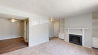 Located at 5850 Laketon Dr in Indianapolis, Indiana, this single-floor, one-bedroom, two-bathroom home offers a functional and comfortable layout. The living room serves as the heart of the space, featuring a classic wood-mantle fireplace flanked by built-in shelving units, neutral-toned carpet, and a sliding glass door that fills the room with natural light and provides outdoor views. Adjacent to the living room, a dedicated dining area features light hardwood-style flooring and a ceiling fan, creating a bright and airy atmosphere. The kitchen is well-appointed with warm wood cabinetry, light countertops, hardwood-style flooring, and white appliances including a range, built-in microwave, and dishwasher. The bedroom is a comfortable retreat with soft carpet, a large sliding glass door with vertical blinds, and ample natural light. A second room provides additional flexible living space. Two bathrooms serve the home, with one featuring hardwood-style flooring and clean white finishes. Two closets and a utility room round out the practical offerings of this well-organized home. The neutral color palette and mix of carpet and hardwood-style flooring throughout create a cohesive and inviting ambiance.