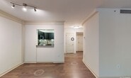 This single-floor residence offers a thoughtfully designed layout that balances modern finishes with comfortable living spaces. The living area is anchored by rich hardwood flooring, decorative columns, crown molding, and a track lighting fixture overhead. Large windows flood the space with natural light and provide views of surrounding greenery, while a pass-through opening connects the living area directly to the kitchen.

The kitchen is outfitted with dark cabinetry, granite countertops, a mosaic tile backsplash, and a full suite of stainless steel appliances including a range, over-the-range microwave, and refrigerator. Light tile flooring completes the clean, contemporary aesthetic.

The bedrooms feature soft carpeting, generous closet space, and windows that bring in ample natural light with outdoor views. The primary bedroom includes a hallway leading to additional closet storage and an en-suite bath.

Both bathrooms are finished with dark vanity cabinetry, granite countertops, undermount sinks, and large-format tile flooring. The primary bath also features a well-lit vanity mirror and built-in shelving. Throughout, the residence maintains a cohesive, neutral color palette that lends itself to a clean and inviting atmosphere.