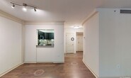 This single-floor residence offers a thoughtfully designed layout that balances modern finishes with comfortable living spaces. The living area is anchored by rich hardwood flooring, decorative columns, crown molding, and a track lighting fixture overhead. Large windows flood the space with natural light and provide views of surrounding greenery, while a pass-through opening connects the living area directly to the kitchen.

The kitchen is outfitted with dark cabinetry, granite countertops, a mosaic tile backsplash, and a full suite of stainless steel appliances including a range, over-the-range microwave, and refrigerator. Light tile flooring completes the clean, contemporary aesthetic.

The bedrooms feature soft carpeting, generous closet space, and windows that bring in ample natural light with outdoor views. The primary bedroom includes a hallway leading to additional closet storage and an en-suite bath.

Both bathrooms are finished with dark vanity cabinetry, granite countertops, undermount sinks, and large-format tile flooring. The primary bath also features a well-lit vanity mirror and built-in shelving. Throughout, the residence maintains a cohesive, neutral color palette that lends itself to a clean and inviting atmosphere.