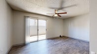Located at 5220 W Northern Ave in Glendale, Arizona, this efficient single-floor unit makes smart use of its space with a well-considered layout. The living room serves as the heart of the home, featuring wood-style flooring, a ceiling fan, a textured ceiling, and a sliding glass door that opens directly onto a private patio, filling the room with natural light and providing easy outdoor access. The combined dining room and kitchen is a functional highlight, showcasing warm wood cabinetry with modern hardware, white countertops, recessed lighting, and black appliances including an electric range and refrigerator, along with a stainless steel sink. A dedicated laundry area accommodates a stacked washer and dryer unit, adding everyday convenience. The bathroom is clean and straightforward, offering a full tub-shower combo with white surround and brushed nickel fixtures. Additional storage is provided through a pantry and a closet, while a hallway connects the various areas of the unit seamlessly. Wood-style flooring runs consistently throughout, giving the space a cohesive, contemporary feel. The unit's layout is practical and efficient, offering all essential amenities within a cozy, manageable footprint ideal for comfortable everyday living.