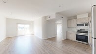 Located at 5501–5513 Laurel Canyon Blvd in Valley Village, Los Angeles, this 2-bedroom, 2-bathroom residence offers a thoughtfully designed single-floor layout with a clean, contemporary aesthetic throughout. Light wood-style flooring flows seamlessly across all living areas, complementing the crisp white walls and recessed lighting that give the space a bright, airy feel.

The open-concept kitchen and living area serves as the heart of the home. The kitchen is outfitted with light wood cabinetry, marble-style countertops, a tile backsplash, and a full suite of stainless steel appliances including a gas range, microwave, dishwasher, and refrigerator. A large window invites natural light into the cooking space.

Sliding glass doors lead from the living area to a private balcony, offering open views of the surrounding Los Angeles neighborhood — a standout feature of this residence. Both bedrooms are generously proportioned, with the primary bedroom featuring its own balcony access and sweeping city views. Each bedroom includes dedicated closet space.

The two bathrooms are well-appointed: one features a glass-enclosed walk-in shower with tile surround, while the second includes a full soaking tub. Additional conveniences include a dedicated laundry area, hallway, and multiple closets for ample storage throughout.