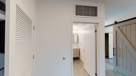 This single-floor space showcases a clean, contemporary design defined by polished concrete floors that flow consistently throughout. The open-concept living area benefits from a generous bank of black-framed windows, flooding the space with natural light and offering views of the surrounding streetscape.

The kitchen is thoughtfully designed with two-tone cabinetry—light wood lower cabinets paired with matte gray upper cabinets—complemented by a white subway tile backsplash, quartz countertops, and a full suite of stainless steel appliances including a gas range, built-in microwave, dishwasher, and side-by-side refrigerator. A butcher block bar-height table with hairpin legs adds a modern accent.

The bedrooms are bright and well-proportioned, each featuring recessed lighting, sliding or hinged closet access, and individual windows. A spacious walk-in closet offers multi-tier wire shelving and hanging rods along all walls for ample storage.

Two bathrooms serve the unit: one features a floating wood vanity, large mirror with medicine cabinets, white tile surround, and a combined tub-shower, while the second offers a walk-in tiled shower stall with polished floors.